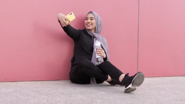 穿着运动服头戴头巾的穆斯林妇女拿着智能手机自拍 — 图库视频影像