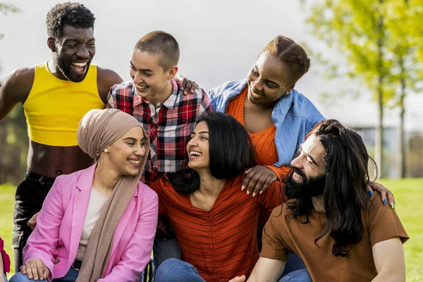 Diverse happy group of people having fun outdoors talking to each other while smiling