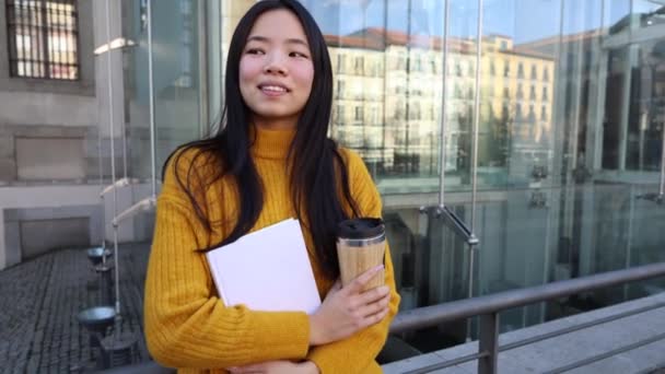 一位漂亮的亚洲女学生在街上带着外卖咖啡和一本书 — 图库视频影像