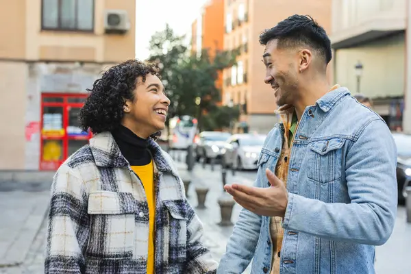 Genç, çok ırklı bir çift şehir merkezinde sokakta konuşuyor ve şakalaşıyor.