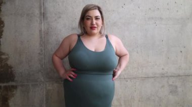 Spor kıyafetleri giymiş, açık havada gülümseyen ve zafer jestleri yapan oldukça mutlu bir kadının yakın plan portresi.