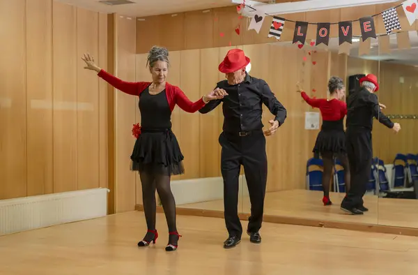 elderly couple giving ballroom dance classes at dance school for retirees