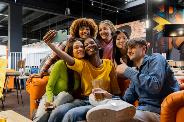 stock image Happy friends taking selfie photo at brewery restaurant - Group of multiracial people enjoying happy hour in arcade - Lifestyle concept with guys and girls hanging out