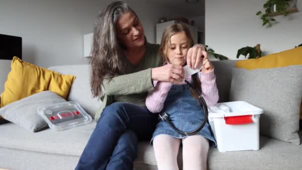 Großmutter Und Enkelin Mit Verbandskasten Auf Dem Heimischen Sofa — Stockvideo