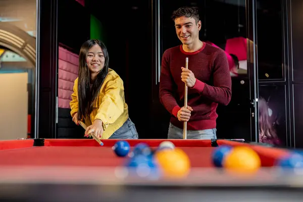 multiracial couple playing pool at bar