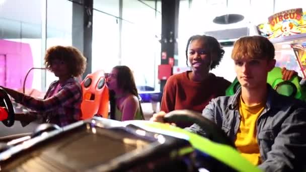 アーケードルームでカーレースシミュレーターをやっている若者のグループ — ストック動画