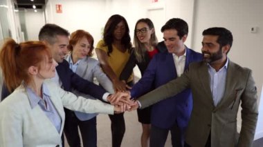Çok ırklı ofis çalışanları ellerini birleştiriyor ve çok nesilli iş birliğini kutluyorlar..