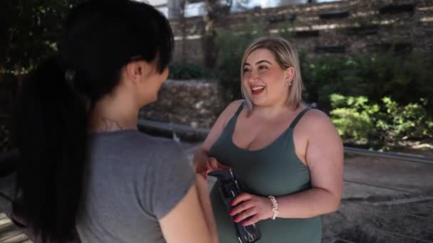 2人の笑顔の女性は 晴れたデッキでトレーニング休憩中にフレンドリーなチャットに参加します — ストック動画