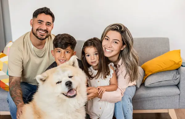Mutlu bir aile poz verir tüylü köpekleriyle, gülümsemelerini paylaşır..