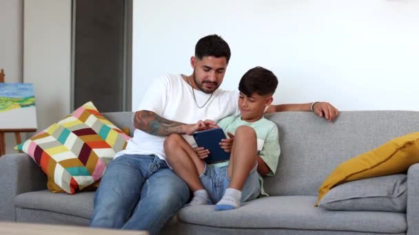 一个纹身的父亲和一个小男孩一起在家里浏览平板电脑 — 图库视频影像