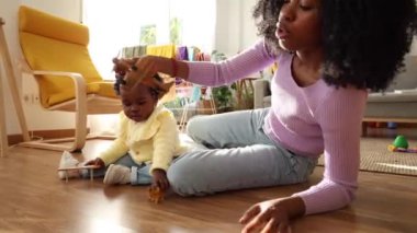 Genç anne yerde tahta oyuncaklar kullanarak çocuğuyla oynuyor..