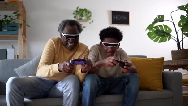 シニアマンと孫として楽しい瞬間は ゲームメガネを着てビデオゲームをします — ストック動画