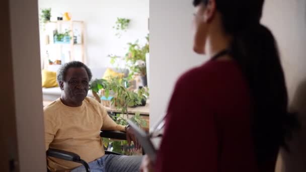 微笑着坐在轮椅上的老人 与一位细心的家庭护理护士聊天 — 图库视频影像
