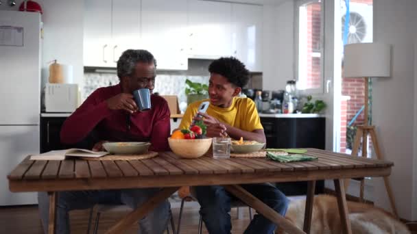 Egy Idősebb Férfi Egy Fiú Beszélgetnek Miközben Tápláló Reggelit Esznek — Stock videók