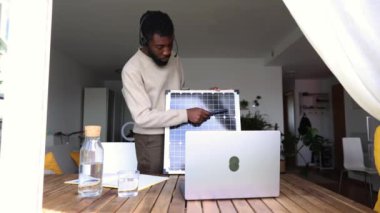 Profesyonel bir Afrikalı Amerikalı danışman uzaktan bir sunum yapar ve ana ofisinden bir güneş panelinin özelliklerini gösterir. Uzak Güneş Teknolojisi Danışmanı Çevrimiçi Sunum Yapıyor