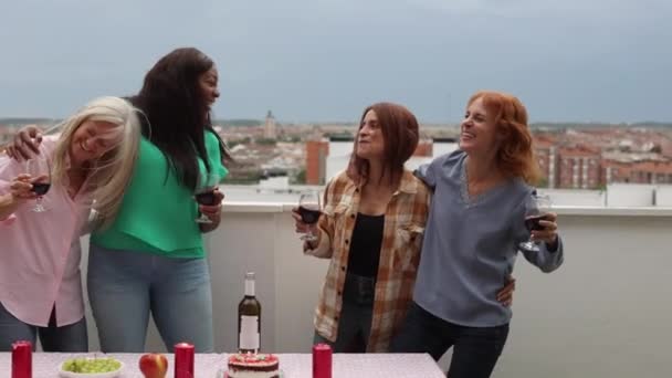 4人の喜びの友人は 街並みを見下ろす屋上にワインのメガネを笑っています ルーフトップ ワイン アーバン スカイラインビュー — ストック動画