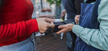 Bir kadın açık terasta yemek yerken temas kurmadan ödeme yapar..