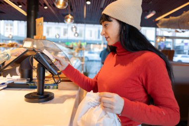 Bir kadın, marketteki pastane ürünleri arasından seçim yapmaktan zevk alır..