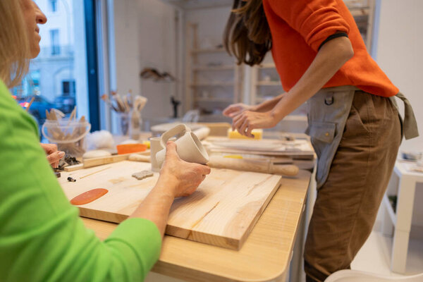 Two women engage in creative pottery making in a bright workshop.