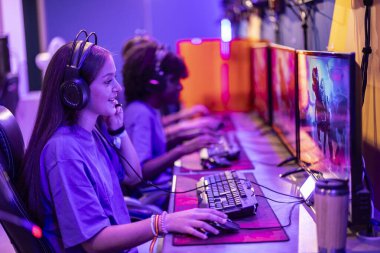 Odaklanmış genç bir oyuncu, işbirlikçi bir eSports oyun oturumu sırasında takımıyla etkileşime girer..