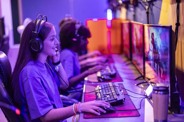 Odaklanmış genç bir oyuncu, işbirlikçi bir eSports oyun oturumu sırasında takımıyla etkileşime girer..