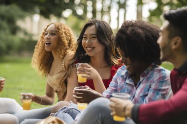 Bir grup gencin parkta içki içerken hikayelerini ve gülümsemelerini paylaştığı samimi bir an..