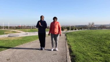 Üst düzey bir erkek ve kadın manzaralı bir parkta yürürken sohbet ediyorlar..