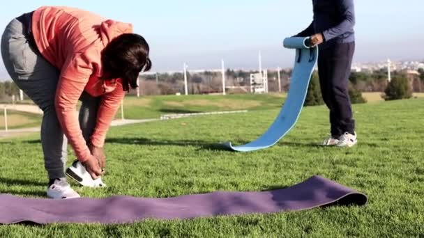 一名老年妇女和一名男子在公园里进行了一次令人神清气爽的锻炼后 把瑜伽垫打包好 — 图库视频影像