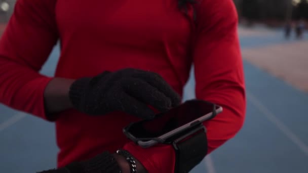 一个穿着红色运动服和高科技眼镜的时髦运动员在跑道上做一个和平的标志 — 图库视频影像