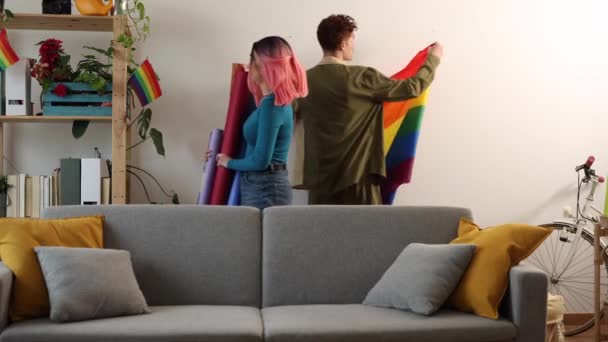 Two Young Adults Enliven Living Space Showcasing Pride Rainbow Flags — Stock Video