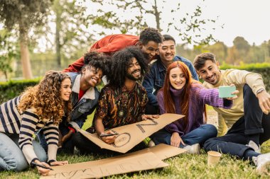 Canlı bir arkadaş grubu grup selfie çekerken, takım çalışması yaparken ve eğlenirken yaratıcı bir projede işbirliği yapıyor..