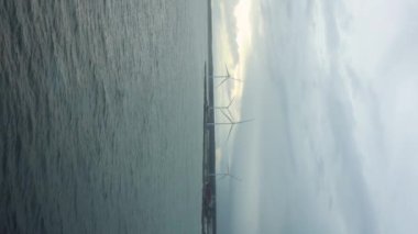Rüzgar türbinleri, yenilenebilir potansiyelin sembolü olan uçsuz bucaksız okyanus üzerinde batan güneşe karşı dururlar. Offshore Rüzgar Türbinleri Okyanus Üzerinde Gün Batımında