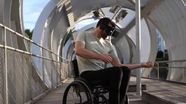 車椅子に乗った中年男性が 現代的な都市環境でVrヘッドセットを使用した仮想環境を探ります — ストック動画