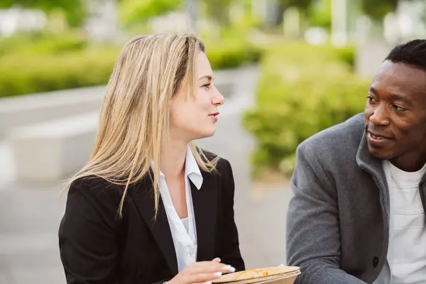 stock image Professional man and woman discussing over a casual meal outdoors, sharing insights.