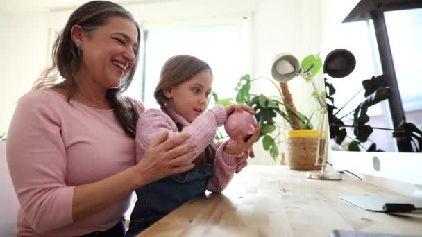 Grandmother Teaches Her Granddaughter Saving Money Using Pink Piggy Bank — стокове відео