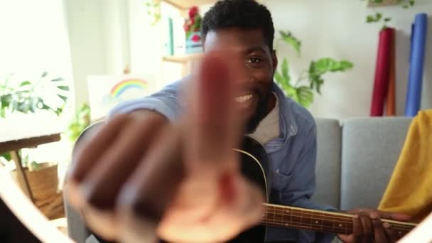 Przyjazny Afrykański Gitarzysta Sięgający Kamery Zapraszający Interakcji Jasnym Wypełnionym Roślinami — Wideo stockowe