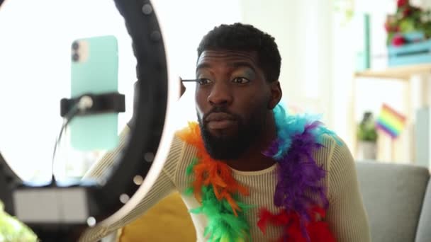 African American Man Applies Vibrant Eye Makeup Exploring Personal Style — Stock Video