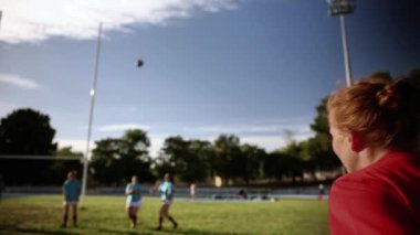 Mavi ve kırmızı formalı bayan rugby oyuncuları bir maç sırasında sahada çekişmeye başladılar..