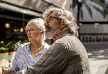 Güneşli bir günde şehri gezerken gözlüklü yaşlı çift etrafa bakıyor..