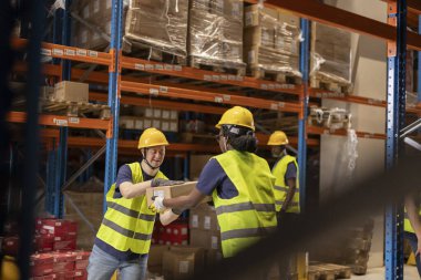 Engelli depo çalışanları kutuları taşımak, dahil etme ve takım çalışmalarını vurgulamak için işbirliği yapıyor.