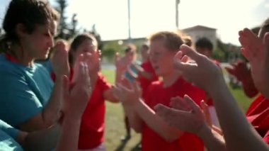 Kırmızı formalı bayan futbolcular alkışlıyor ve tezahürat yapıyor, sahada takım ruhu ve birlik gösteriyor..