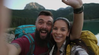 Sırt çantalı neşeli çift dağ yürüyüşü sırasında manzaralı selfie çekiyor..