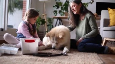 Yaşlı bir kadın ve genç bir kız büyük bir köpekle ilgileniyor, sıcak bir oturma odasının zemininde otururken bir bağ anı yaratıyorlar..