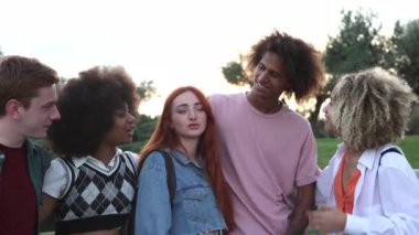 Bir patikada kol kola yürüyen, sırt çantalarıyla okula giden, gayri resmi bir anın tadını çıkaran çok ırklı bir grup öğrenci..