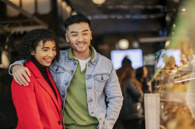 Mutlu çift gülümsüyor ve kalabalık bir markette eğleniyorlar..