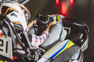 Başlık takmış bir yarışçının go-kart sürüşünün detaylı görüntüsü, kapalı alandaki piste odaklanmış..