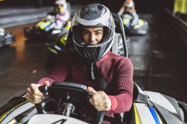 Kask takan, go-kart yarışına hazırlanan genç bir adamın yakın çekimi..