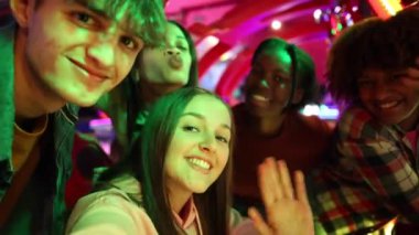 Neşeli bir oyun salonunda selfie çeken, gülümseyen ve eğlenen bir grup genç..