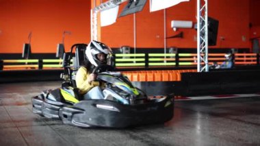 Kapalı pistte go-kart süren genç, renkli engelleri aşmak için rekabetçi bir ortamda yarışıyor..