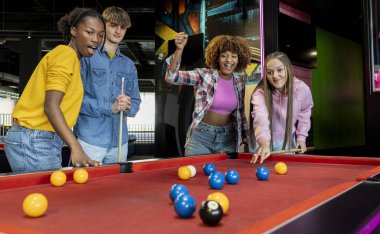 Bir grup arkadaş hevesle bilardo oynuyor, tezahürat yapıyor ve oyunlara tepki veriyorlar..